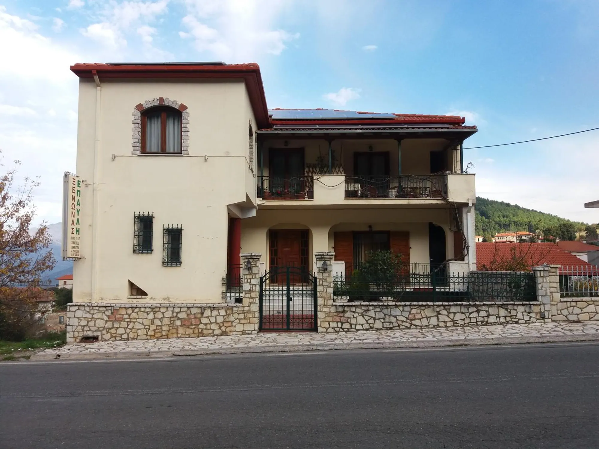 Το διώροφο κτίριο του ξενώνα με τα μπαλκόνια, από τον δρόμο